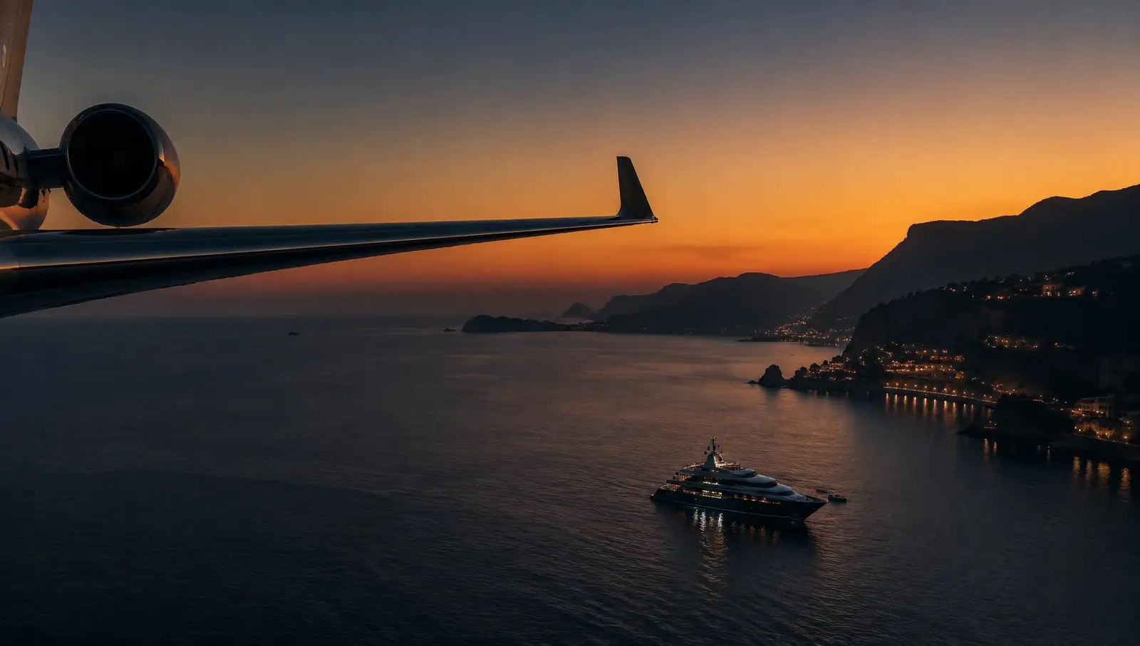 Private jet wing above a coastline at dusk with a yacht at anchor